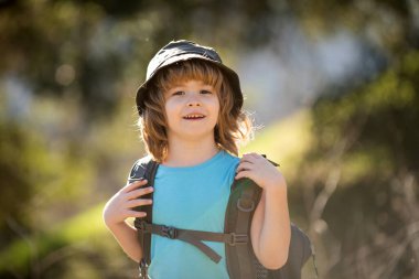 Sırt çantalı küçük bir çocuk manzaralı dağlarda yürüyüş yapıyor. Çocuk yerel bir turist yerel bir yürüyüşe çıkıyor.