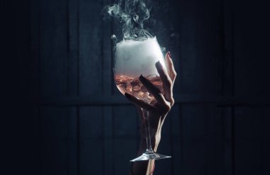 Yakın plan kadın elinde gizemli beyaz kristal sıvıdan yapılmış şarap kadehi ve ahşap arka planda köpük var..