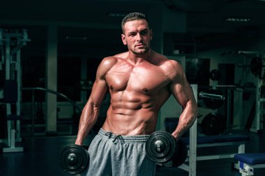 Spor salonunda halterli vücut geliştirici eğitimi. Çıplak gövdeli bir sporcu. Sportif egzersiz. Atletik vücut.