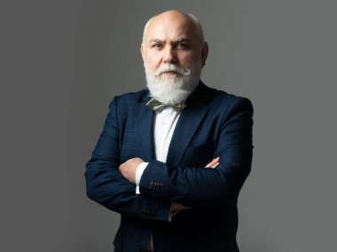 Kıdemli Takım Elbiseli Adam, 60 yaşında. Olgun iş adamı gri kameraya bakıyor..