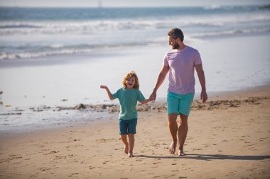 Baba ve oğul denizde yürüyor. Baba ve çocuk dışarıda eğleniyor..