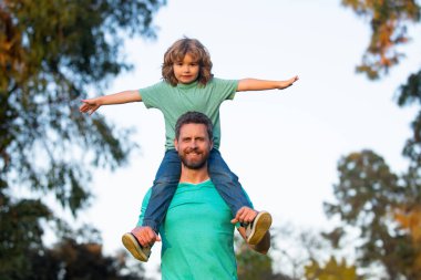 Mutlu babadan oğula. Küçük çocuk babasının omuzlarında.