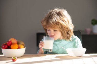 Süt bardağı içen çocuk. Sevimli küçük çocuk, camdan vitaminli kalsiyum içeren lezzetli organik süt içiyor. Küçük çocuk lezzetli besleyici laktozsuz yoğurdun tadını çıkarıyor. Sağlık hizmetleri kavramı.