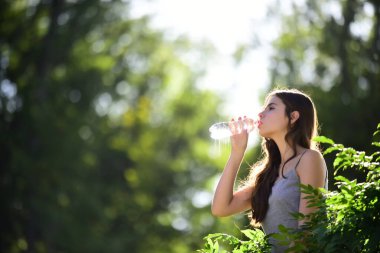 Şişeden su içen sağlıklı bir kadın. Susuz kalma konsepti. Susuz kalmış. Doğayla birlik, açık hava.