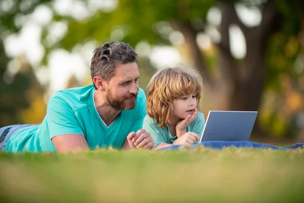 Pai e filho menino da escola com laptop. Pai e criança uso notebook tablet ao ar livre. — Fotografia de Stock