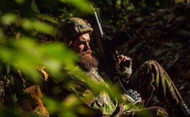 Askeri miğferli, üzgün yüzlü ve silahlı bir asker.