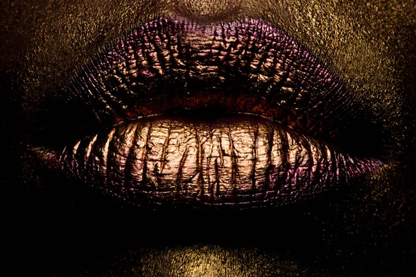 Golden lips closeup. Gold metal lip. Beautiful makeup. Golden lip gloss on beauty female mouth, closeup.