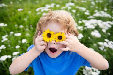 Komik çocuk dışarıda eğleniyor. Çocuk yaz parkında oynuyor. Yeşil çimlerin üzerinde küçük bir çocuk.