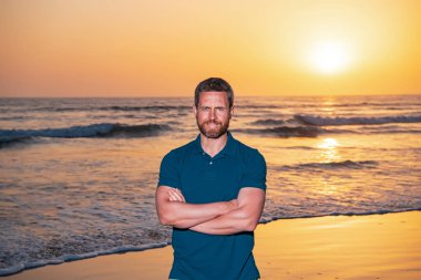 Yakışıklı, gülümseyen adam sahilde yaz gününün tadını çıkarıyor..