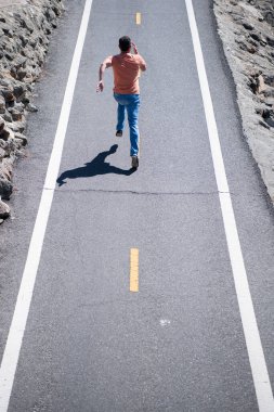 Yolda koşan bir adamın arka görüntüsü. Atletik genç adam dışarıda koşuyor..