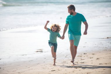 Baba ve oğul yaz plajında koşuyor. Mutlu aile kavramı.