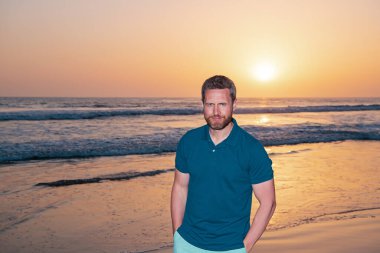 Denizde ya da okyanusta yakışıklı bir adam. Gün batımında Kafkasyalı yetişkinler gibi rahatla..