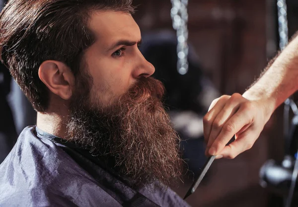 Een man met baard in een kapperszaak. Kapper kam. Vintage kapperszaak, scheren. Portret van een man met een baard. Snorremannen. Brutale vent, schaar, scheermes. — Stockfoto