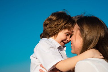Annelik. Çocuk evlat, anneye sarıl. Anne ve çocuk gülümsüyor ve sarılıyorlar. Aile tatili ve birliktelik.