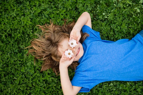 Niño feliz acostado en la hierba en el día de primavera. —  Fotos de Stock