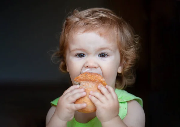 Retrato de bebê engraçado com pão nas mãos comendo. Criança bonito comendo sanduíche, conceito de auto-alimentação. — Fotografia de Stock