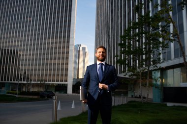 Ofis binasında dikilirken takım elbiseli yakışıklı bir orta yaşlı iş adamı..