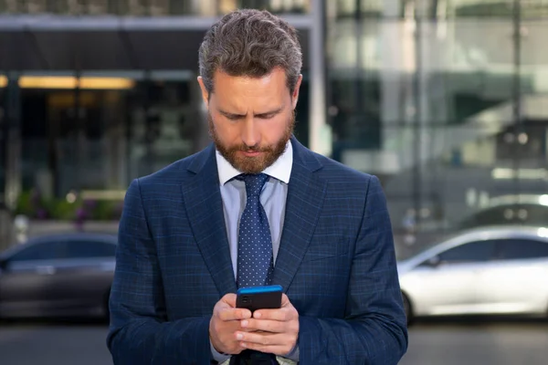 Geschäftsmann schreibt SMS auf Smartphone in der Nähe des Büros. — Stockfoto