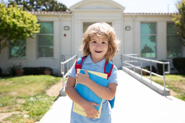 Criança com mochilas em pé no parque perto da escola. Alunos com livros e mochilas ao ar livre. Miúdo com mochila a ir para a escola. Conceito de educação infantil. — Fotografia de Stock