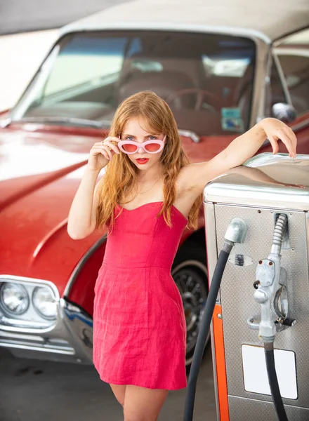 Menina retro sexy com carro. Posto de gasolina, a mulher abastece o carro. Automóvel retro vermelho. — Fotografia de Stock