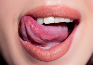 Seksi dudaklar, yakın çekim. Dilini yalayan şehvetli bir ağız. Baştan çıkarıcı dudak makyajı.