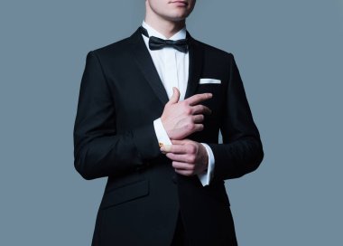 İş görünüşü. Kol düğmelerini tamir eden adam. Erkek giyimi modası. Siyah takım elbiseli beyefendi. Zarif ve şık kıyafetler..