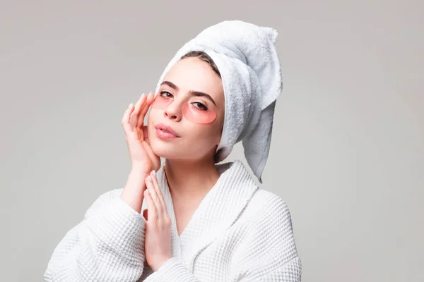 Retrato de mujer de belleza con parches en los ojos que muestran un efecto de la piel perfecta. Bajo las máscaras para la hinchazón, las arrugas, las ojeras. Mujer sexy en albornoz blanco aplicando parches para los ojos. — Foto de Stock