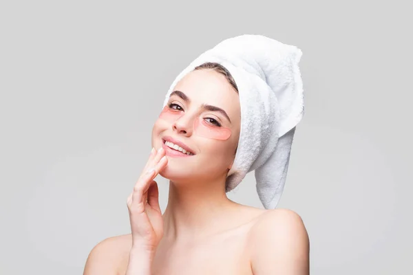 Счастливая женщина надевает повязки на глаза. Закрыть портрет девушки с полотенцем на голове. Портрет красавицы с повязками на глазу, показывающий эффект идеальной кожи. — стоковое фото