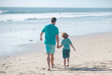 Baba ve çocuk dışarıda eğleniyor. Çocukluk ve ebeveynlik kavramı. Baba oğul yaz plajında yürüyorlar..