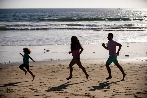 ビーチでお父さん、お母さん、子供のジョギング。健康的な家庭生活をコンセプトとする。夏休みの海で。スポーツ活動、家族のコンセプトを実行する. — ストック写真