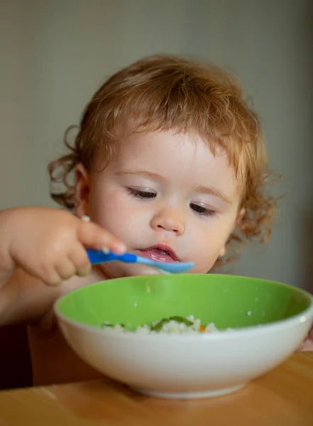 Engraçado bebê na cozinha comendo com os dedos de prato. — Fotografia de Stock