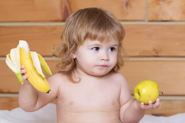 幸せな赤ちゃんの子供はリンゴとバナナを食べる. — ストック写真