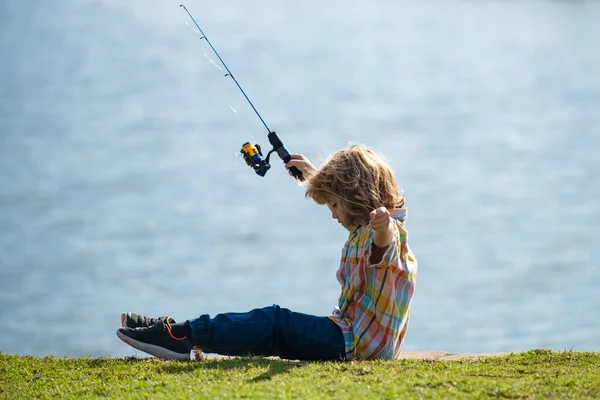 子供釣り。若い漁師だ。川でスピナーを持つ少年。湖の上の棒で桟橋で興味のある少年釣りの肖像画。釣りの概念. — ストック写真