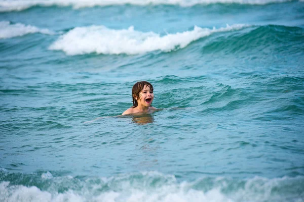 Garoto brincando e nadando no mar azul no verão. Oceano azul com wawes. Menino nadando no mar. — Fotografia de Stock