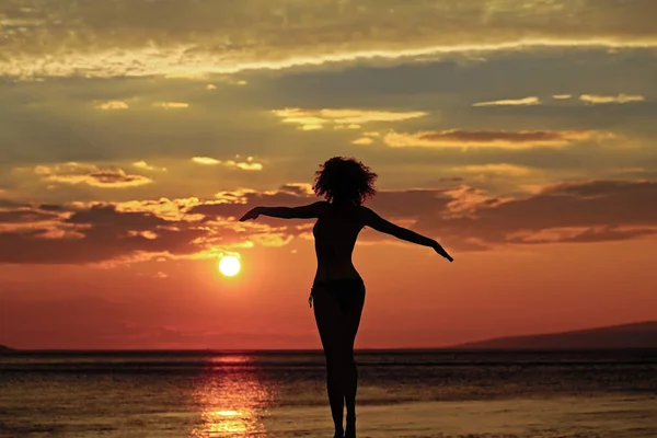 夜や夕暮れ時に海や海の水の近くのビーチで女性のシルエット自然背景に夏の日. — ストック写真