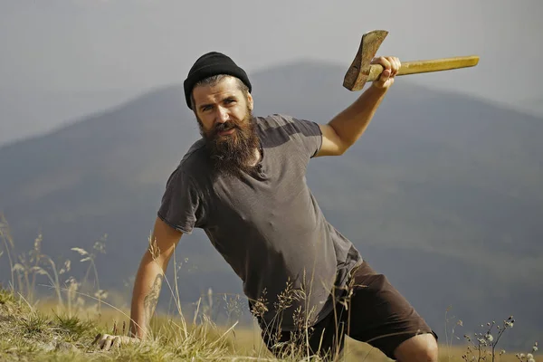 Bûcheron homme à longue barbe tenant hache sur le sommet de la montagne sur fond naturel — Photo
