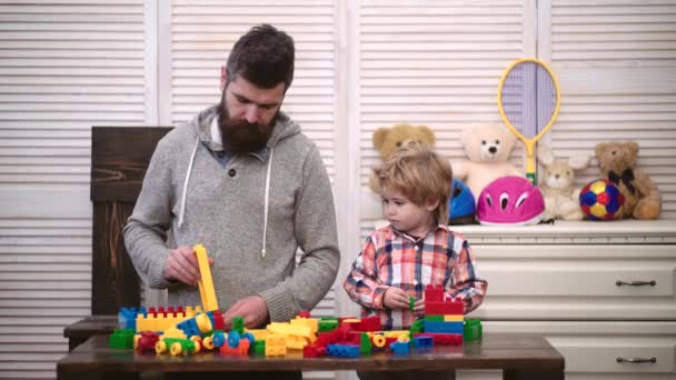 Faderskap. Barn med leksaksbrickor. Pappa leker konstruktör med sin son. Glad unge som leker med pappa. Flerfärgade block. — Stockvideo