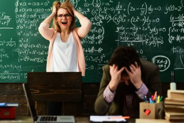 Gözlüklü üzgün öğretmen, yetenekli öğrencilerin hataları düzelttiği raporlarını okuyor..