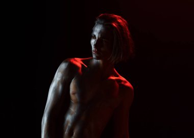 Adam kendine güvenerek poz veriyor. Çıplak gövdeli bir adam. Çıplak göğüslü seksi maço. Atletik figür kavramı.