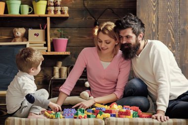 Mutlu bir aile. Çocuklar oyuncaklarla oynuyor. Baba, anne ve tatlı oğul inşaatçı tuğlalarıyla oynuyorlar. İlgili ebeveyn kavramı.