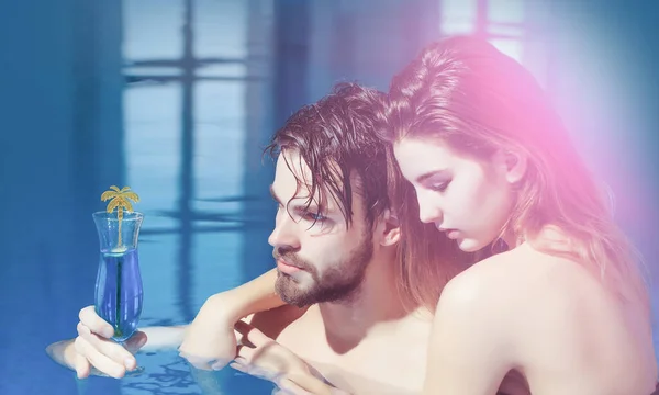 Havuzdaki güzel kadın ya da seksi kız ve yakışıklı sakallı adam ya da yüzme havuzunda mavi suyu olan kaslı adam kokteyl bardağı tutuyorlar.. — Stok fotoğraf