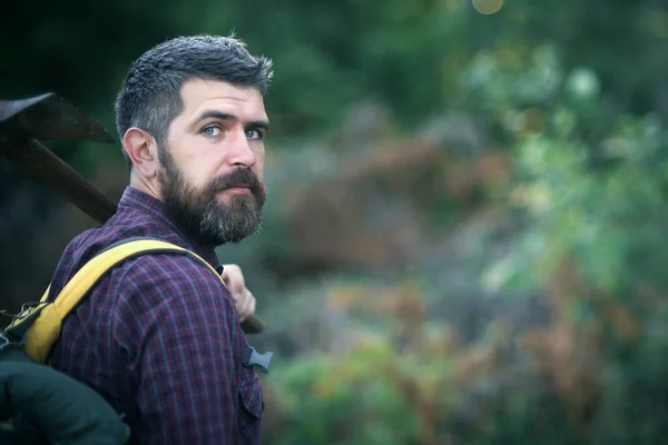 Hombre excursionista mantenga hacha y mochila en el día de verano en el paisaje natural. — Foto de Stock