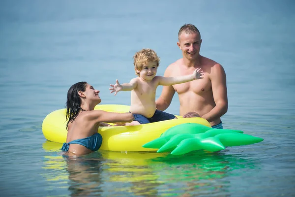 父亲和母亲带着儿子在水里玩球。马尔代夫或迈阿密海滩活动的乐趣。加勒比海上快乐的家庭伴侣。暑假和海洋旅行. — 图库照片
