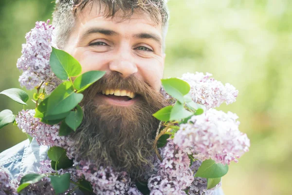 Berd en fleurs. Homme barbu souriant dans le jardin de campagne tenant des branches lilas. Fleuriste masculin prenant soin du verger en fleurs, concept de printemps. Visage de l'homme heureux sur fond naturel. — Photo