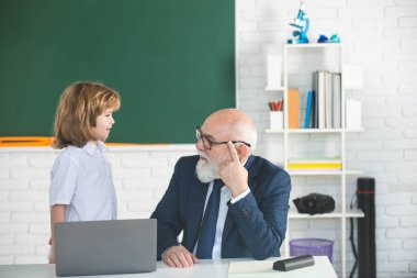 Dizüstü bilgisayarı olan eski öğretmen. Çevrimiçi eğitim kavramı. Okul dersi. Sınıfta okul çocuğuyla öğretmen. Öğrenmek için yardım.