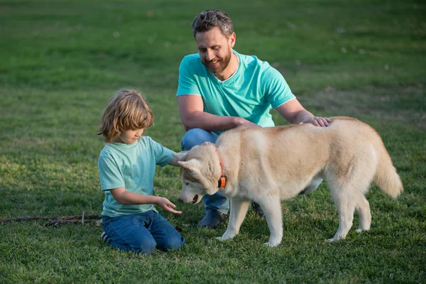 Köpekli neşeli çocuk. Baba ve oğlu yaz parkında yürüyor. Sağ tarafta uzayı kopyala. Tam boy portre. Çocuk köpekle yürüyor.. — Stok fotoğraf