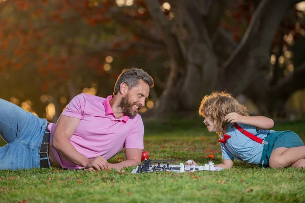 Father and son playing chess spending time together outdoor. Intelligent child, smart kids.