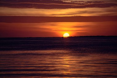 Okyanus suyunun üzerinde doğal gün batımı. Dramatik bir gökyüzü. Renkli gökyüzünün altında deniz manzarası. Ufuk çizgisinde gün doğumu güneşi. Sıcak Renkler.