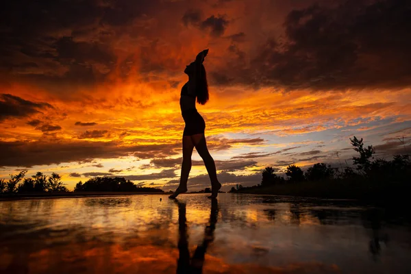 Schwarze Silhouette von hübschen Mädchen oder schöne Frau, sexy schlankes Modell, mit langen Haaren posiert am Strand bei Sonnenuntergang im Freien auf gelbem Himmel Hintergrund — Stockfoto