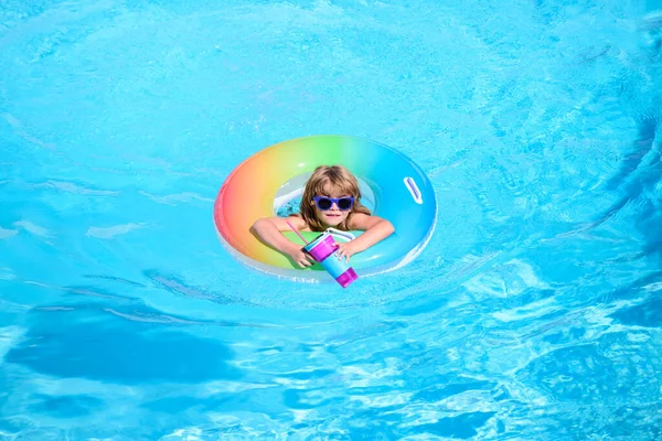 在游泳池里的孩子，在充气环上放松地游泳，暑假在水里玩乐，蓝水背景，复制空间。全景蓝色海浪. — 图库照片